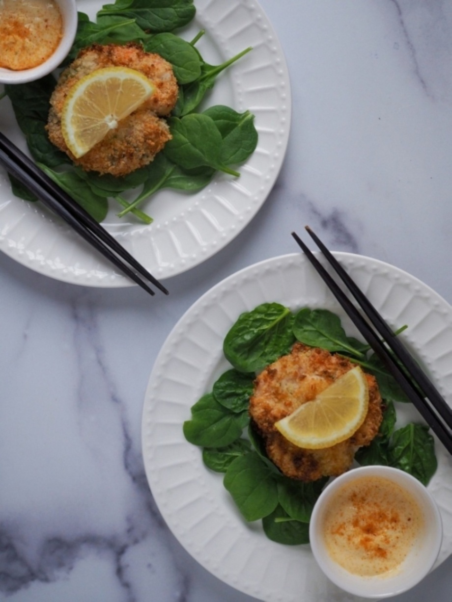 Breaded shrimp patty plated on a bed of greens, garnished with lemon